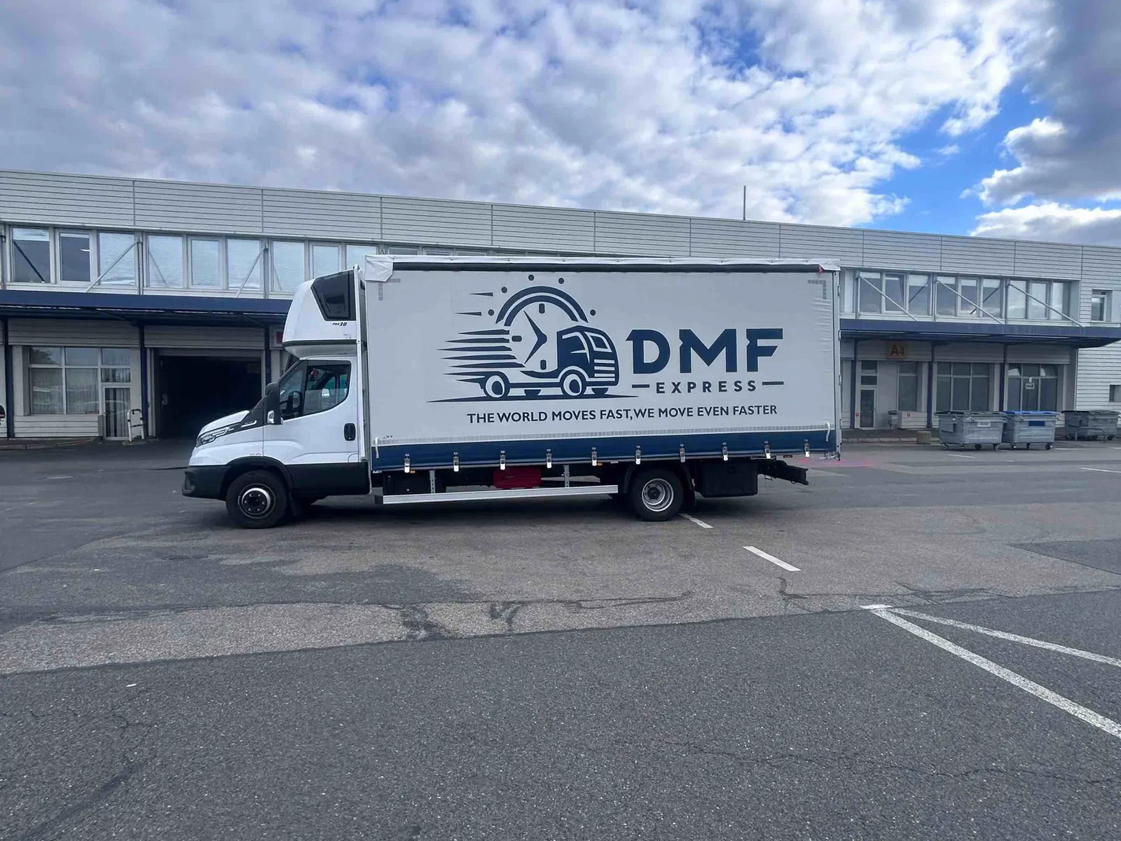 7,2-t-Planenfahrzeug von DMF Express vor einem Lager mit Laderampen