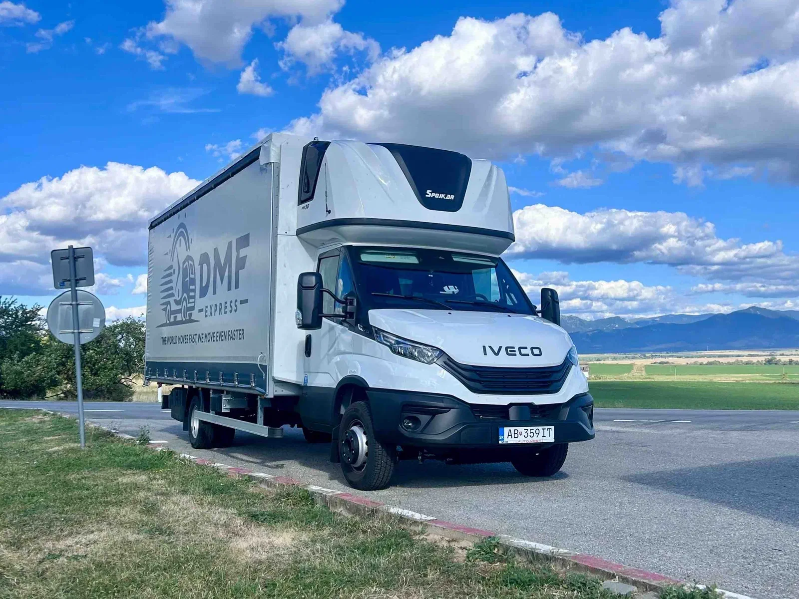 7,2-t-Planenfahrzeug Iveco Daily von DMF Express am Straßenrand mit Bergen im Hintergrund